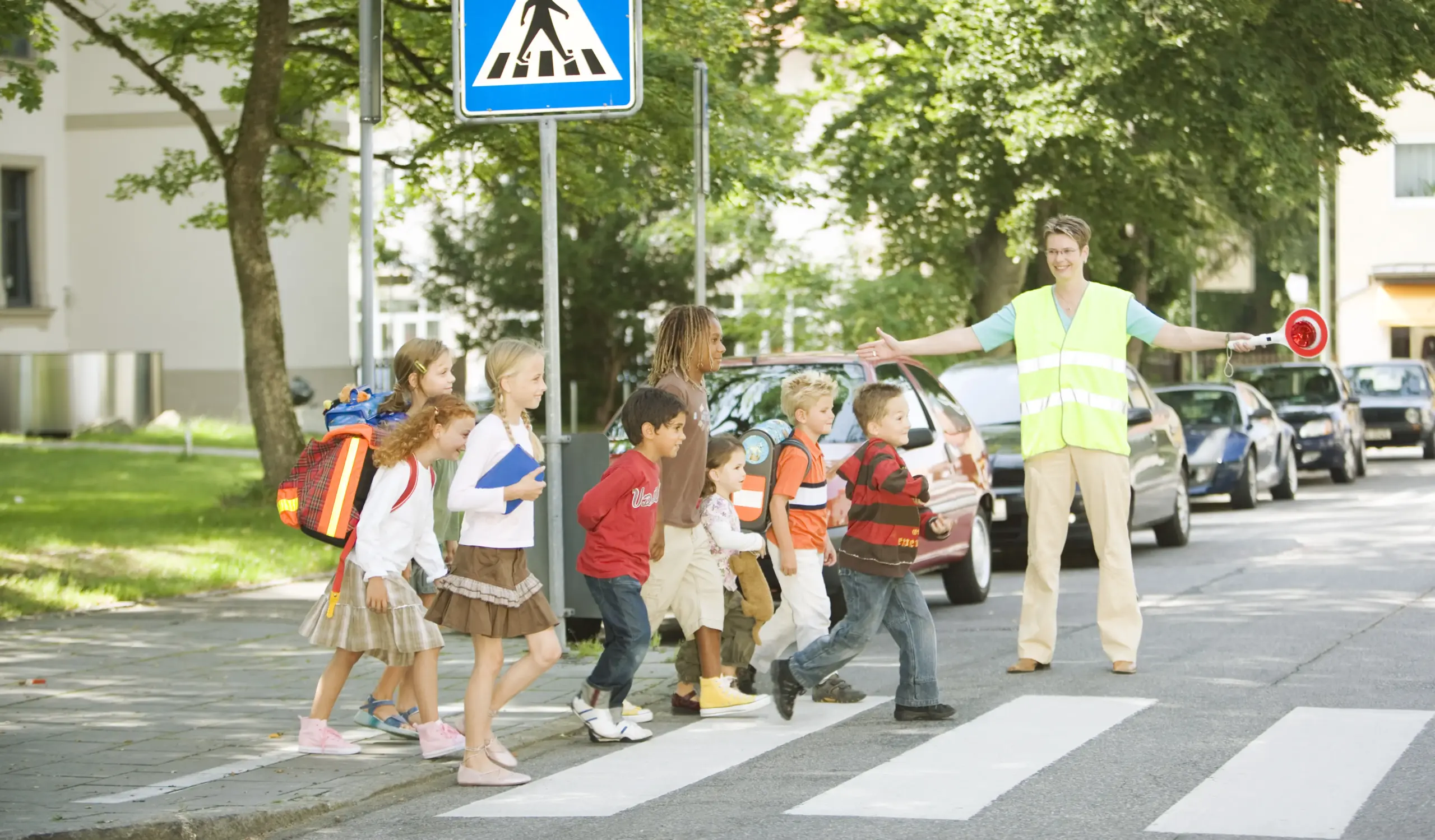 Schulkinder überqueren gemeinsam mit einer Verkehrshelferin einen Zebrastreifen zum Schulstart in Koblenz